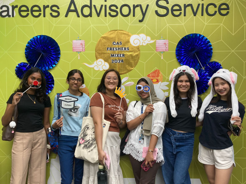 Group of new students posing with photo props inside the Career Advisory Service office.