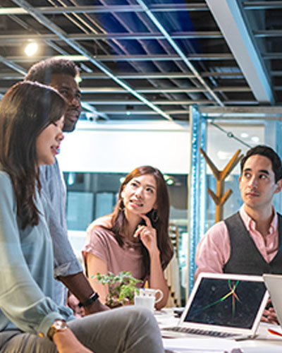 four people is having a discussion in front of the laptop on the table